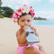 Baby using Squooshi reusable food pouch on beach, wearing flower crown.