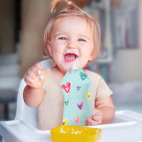 Baby enjoying food from Squooshi heart and star reusable food pouch.